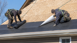 Two roofers installing ice and water shield on a residential roof deck before the finished roofing is applied.